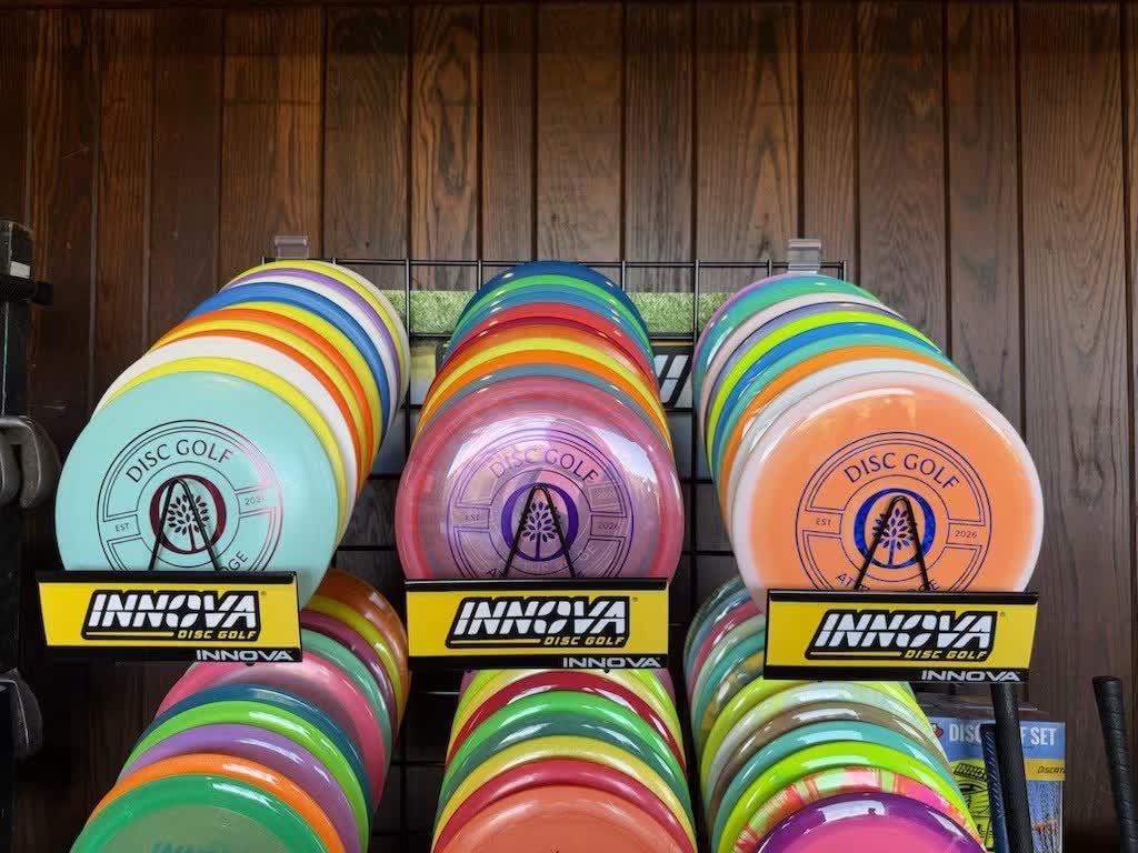 Racks of Innova discs for sale at the Oglebay Park Resort driving range, with custom Oglebay Disc Golf 'At The Ridge' stamped discs across the top row